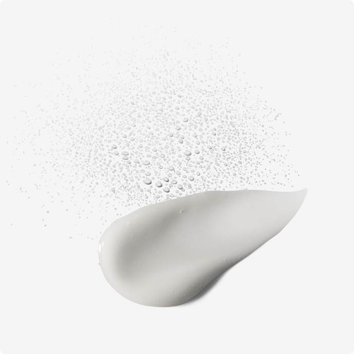 Close-up of a droplet of white lotion on a light gray background